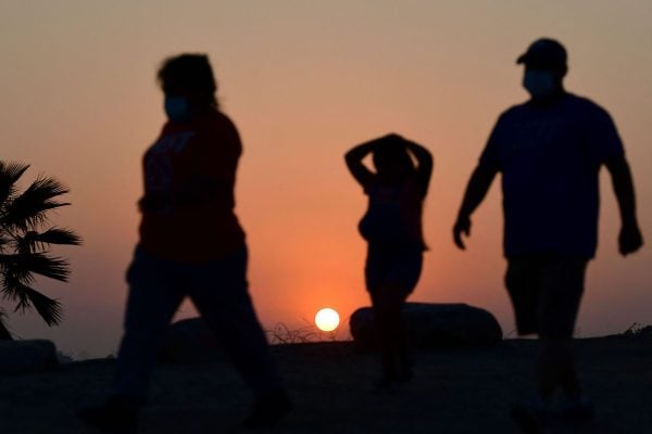 The sun sets behind people walking an afternoon hike.