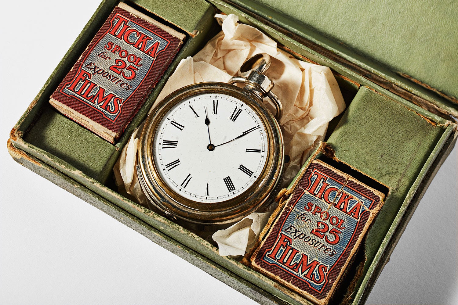 a close up of a vintage watch-shaped camera with films, isolated on a background