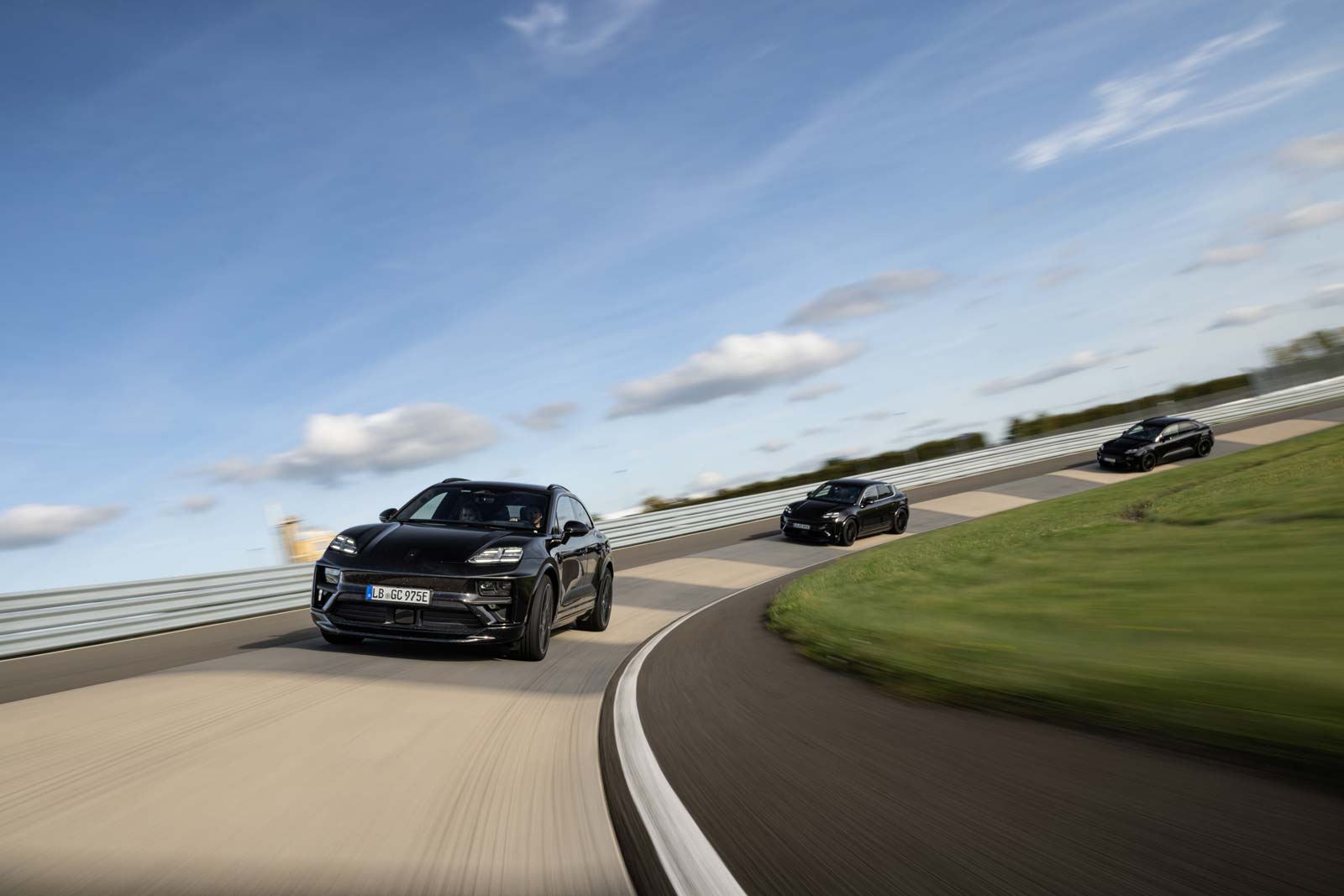 A line of Porsche Macan SUVs going around a track corner