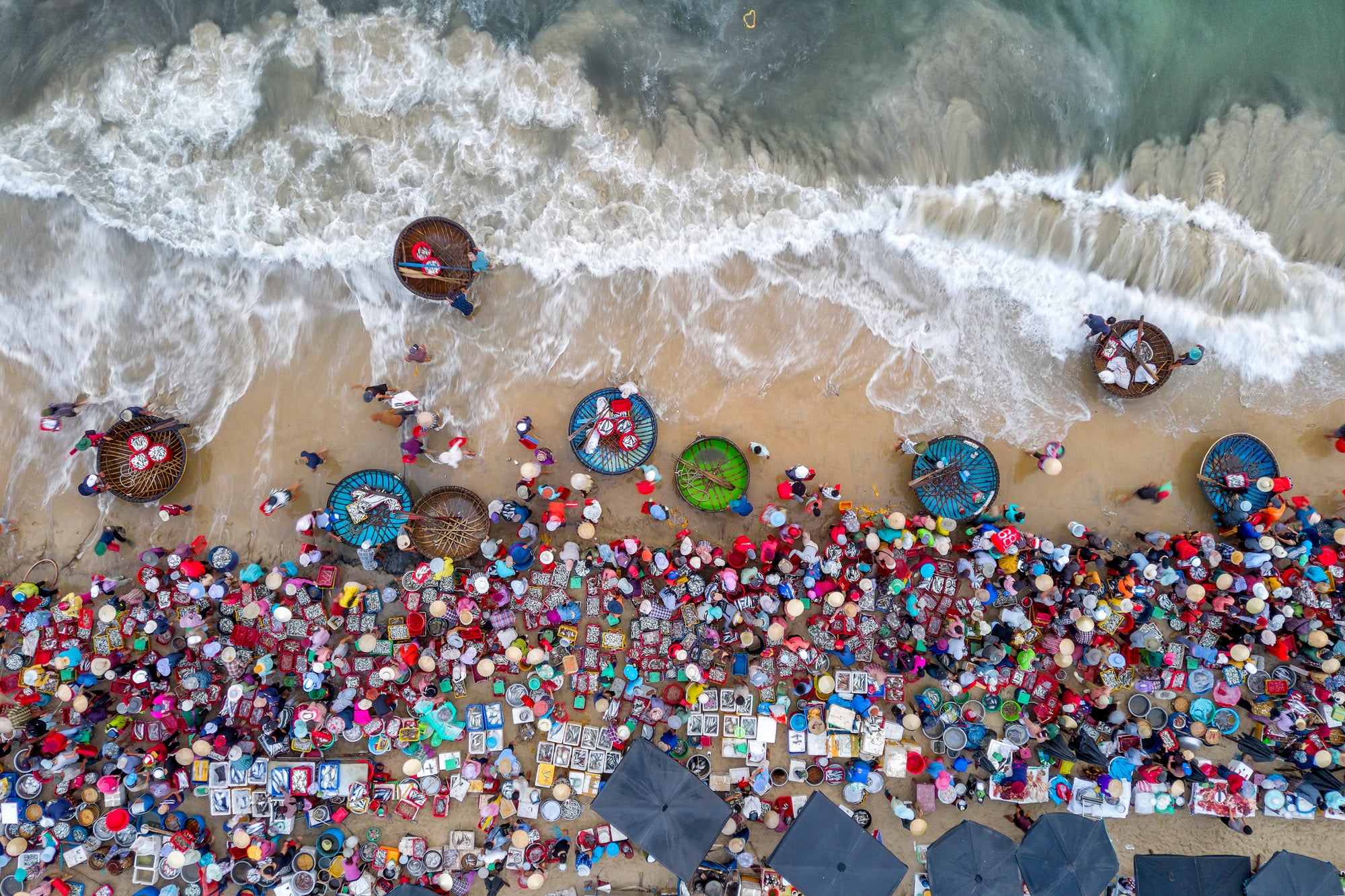 Overhead perspective above a beach filled with people and fish baskets