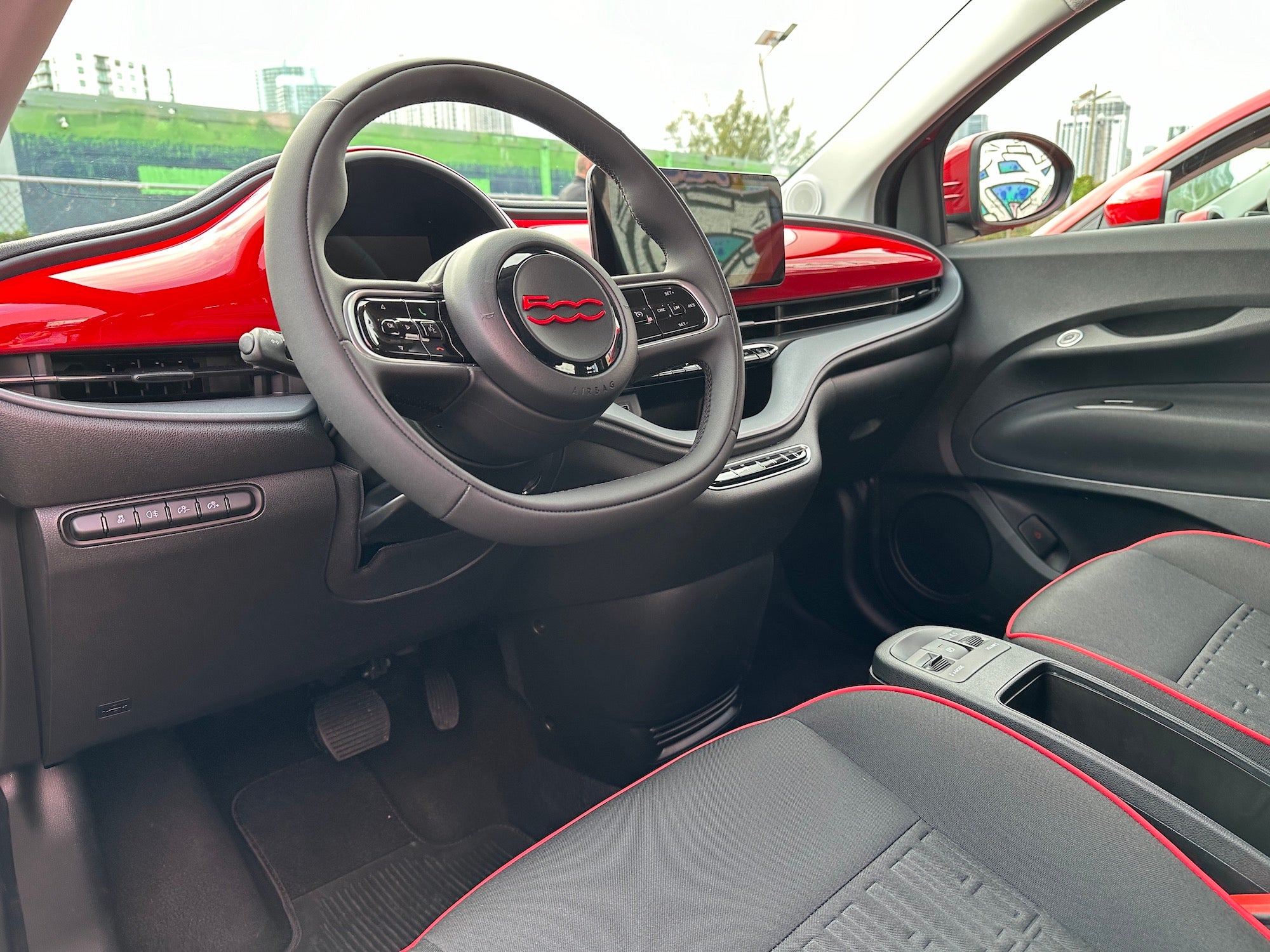 black and red interior of a fiat, showing two front seats, steering wheel, and screen