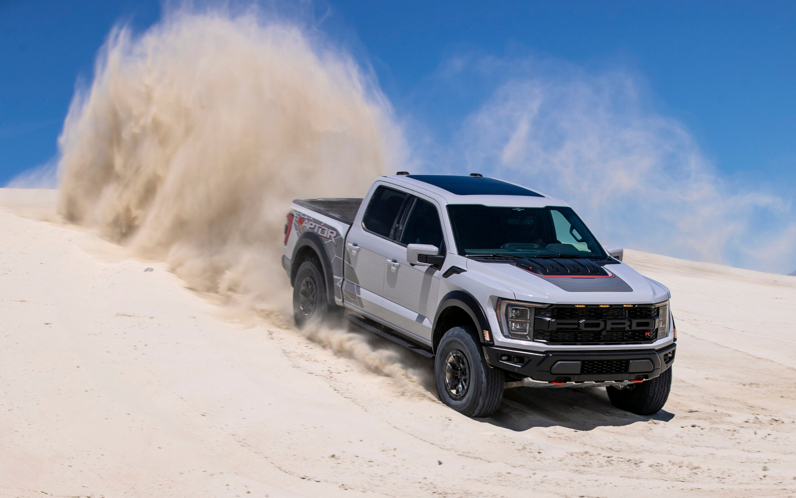 a grey pickup truck drives through the desert