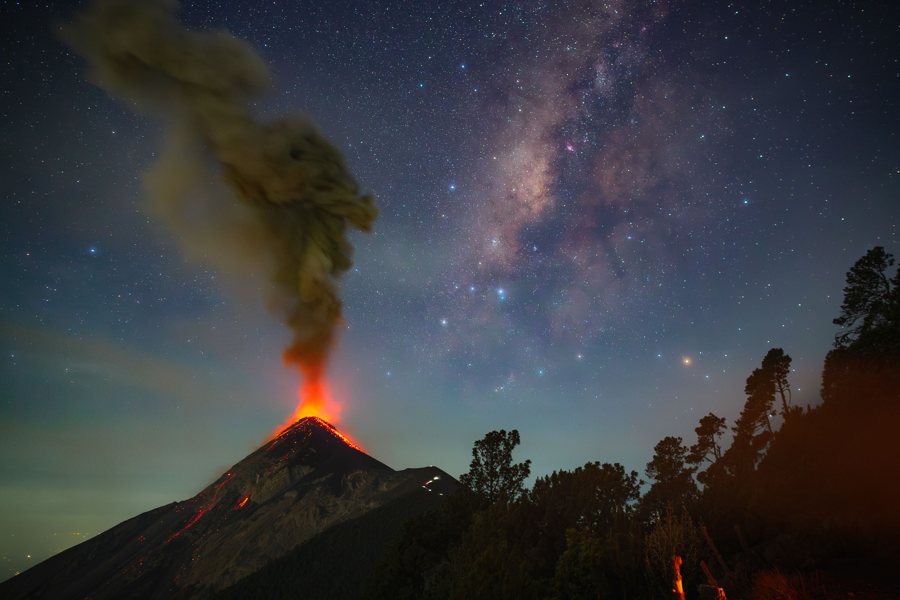 an erupting volcano under milky way