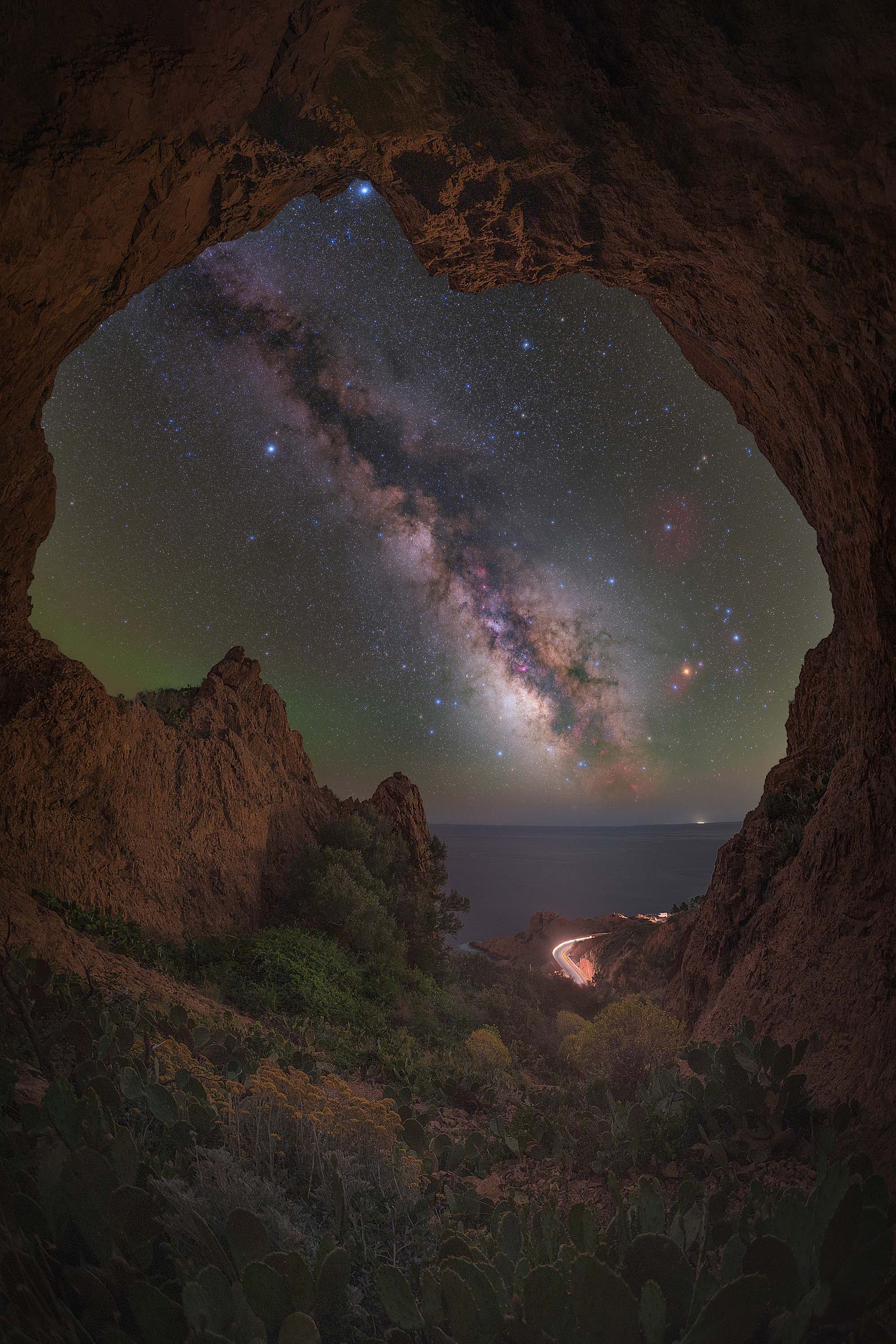 round cut out of a cave frames the milky way