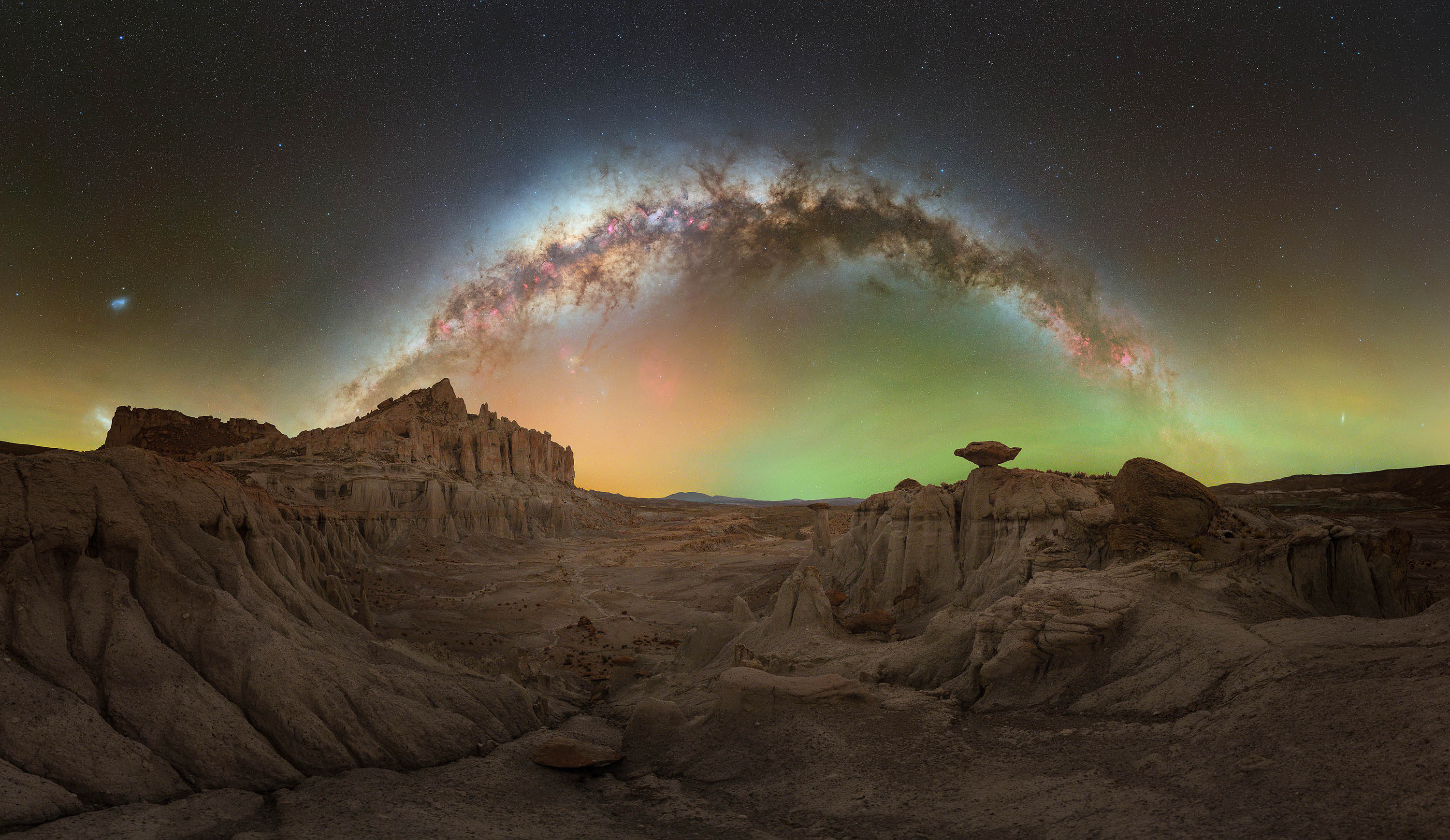 an arch of the milky way over a rocky landscape