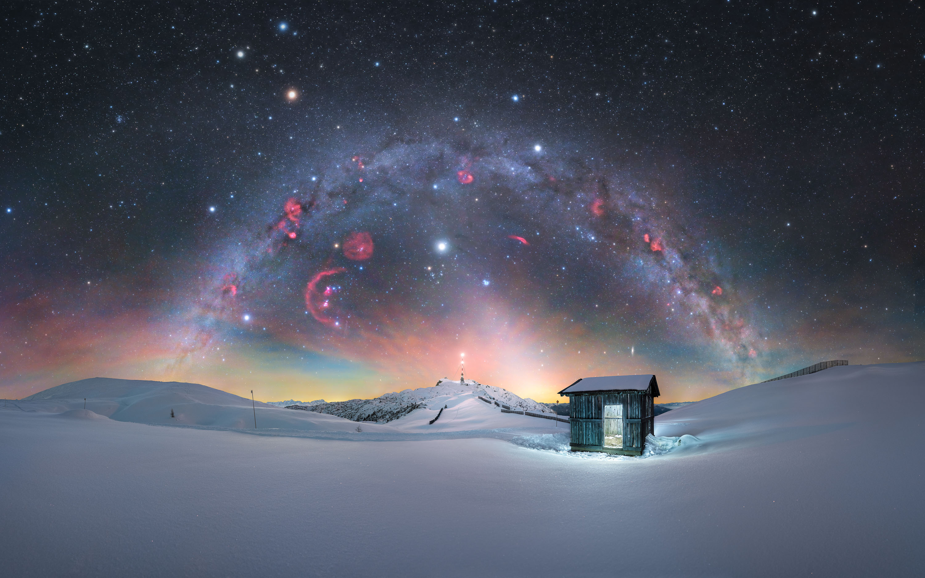 arching milky way over snowy landscape and shack
