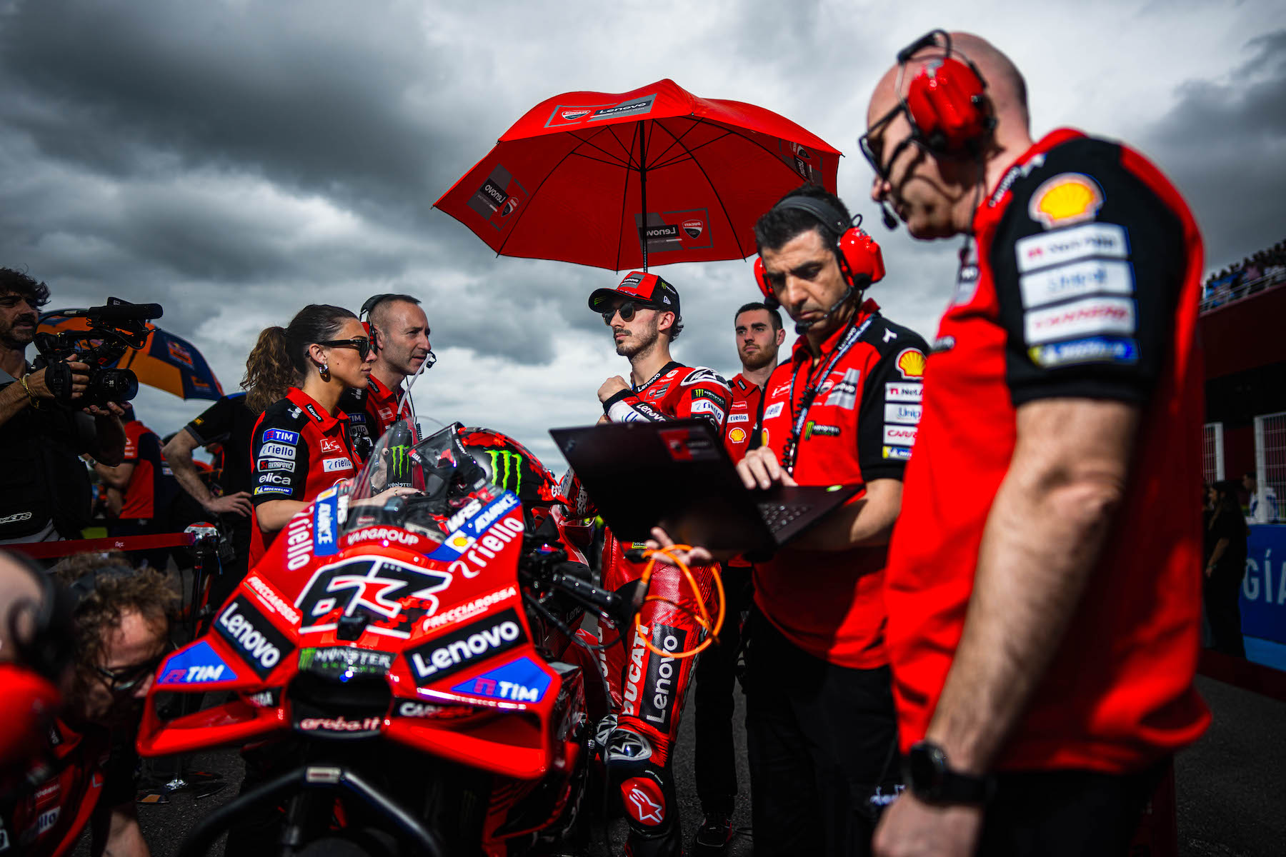 a team surrounds a driver while a man holds a computer