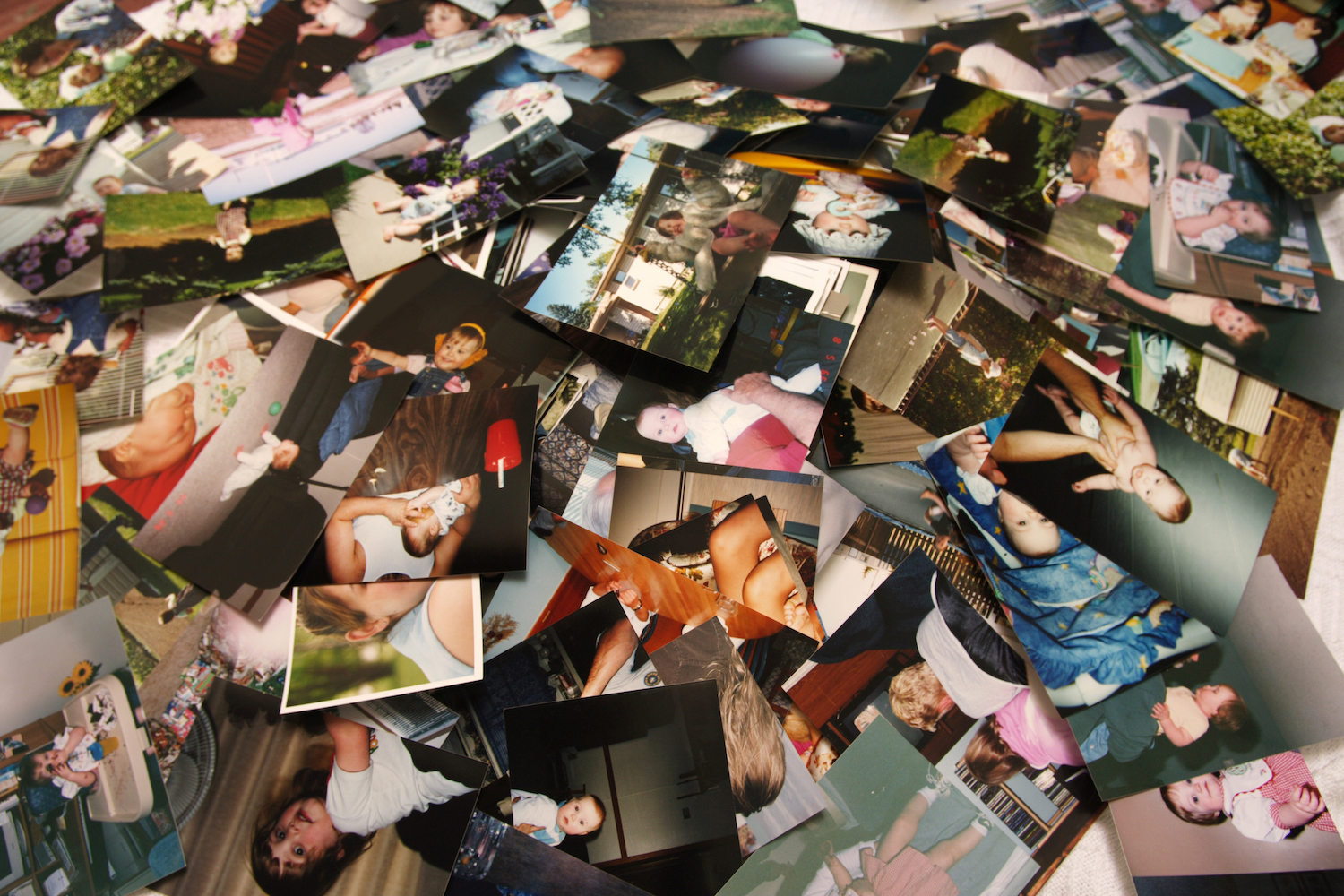 Precious, nostalgic memories captured and displayed in a chaotic pile of random, unsorted printed pictures of a cute little girl through various stages of her life, beginning as an infant, up until she is about four years old. A scrapbooker's nightmare, or treasure chest!