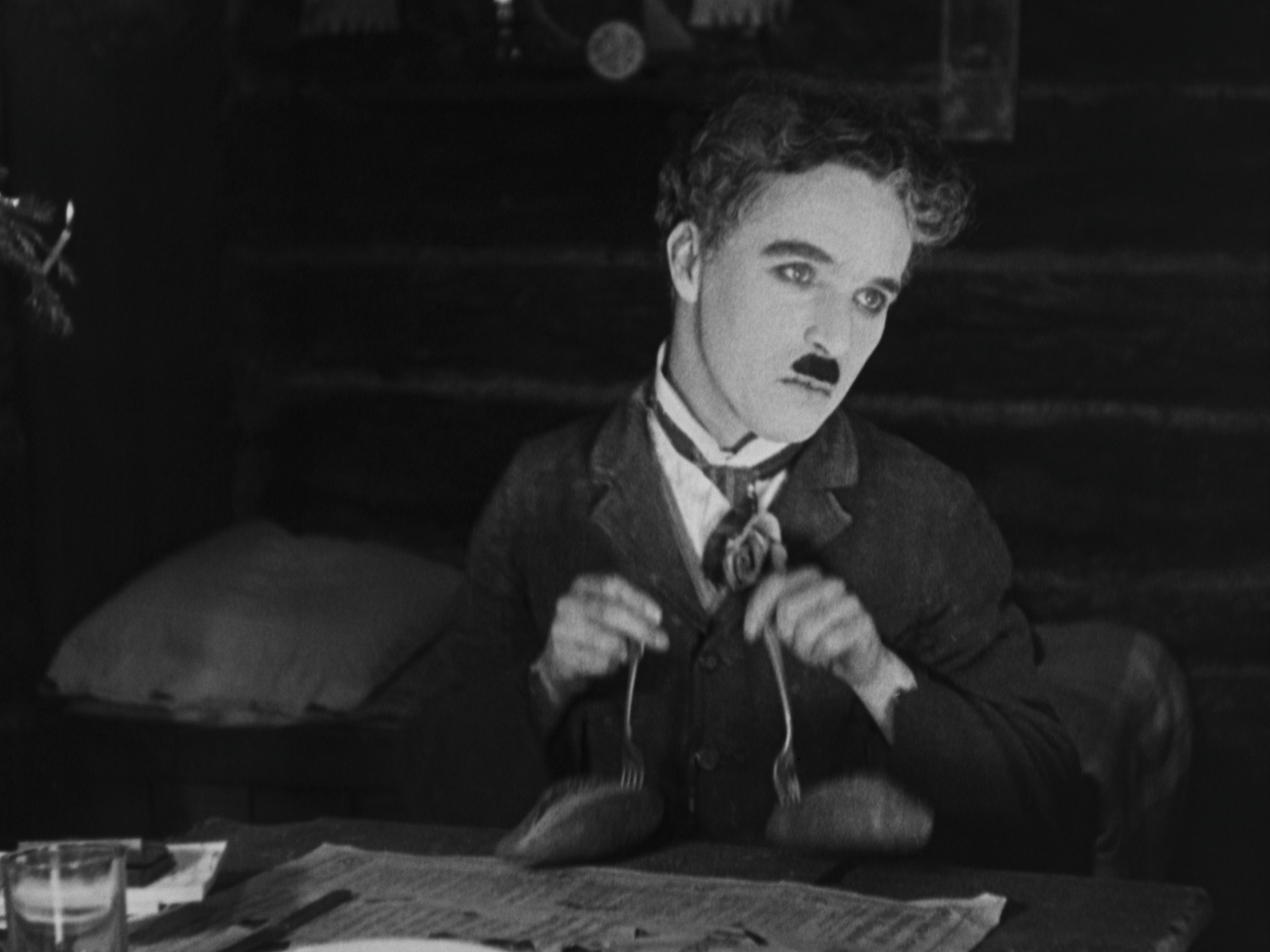 Charlie Chaplin playing with potatoes in famous scene from The Gold Rush
