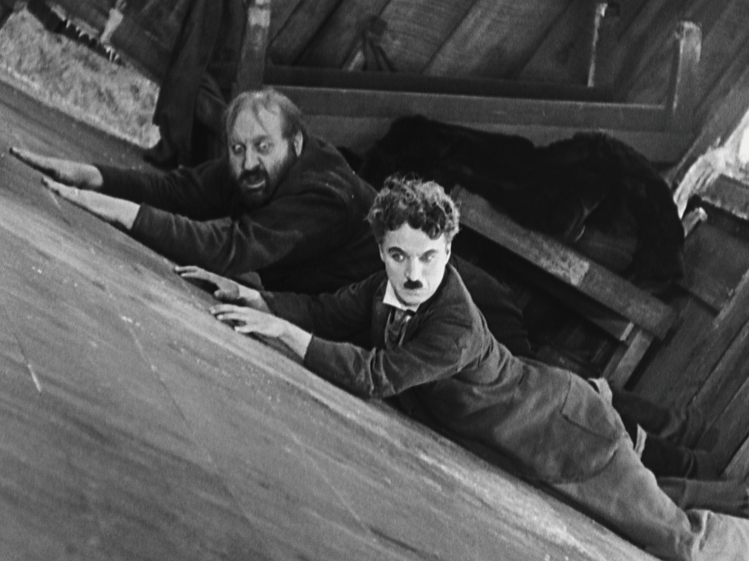 Two men sliding down a cabin floor as it tilts