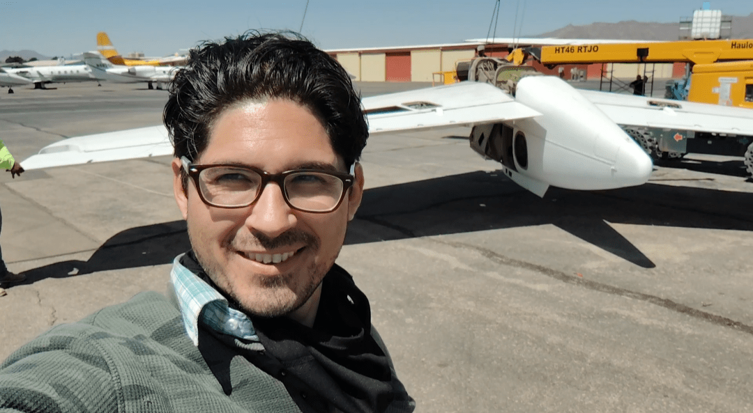 man taking selfie with plane piece in background