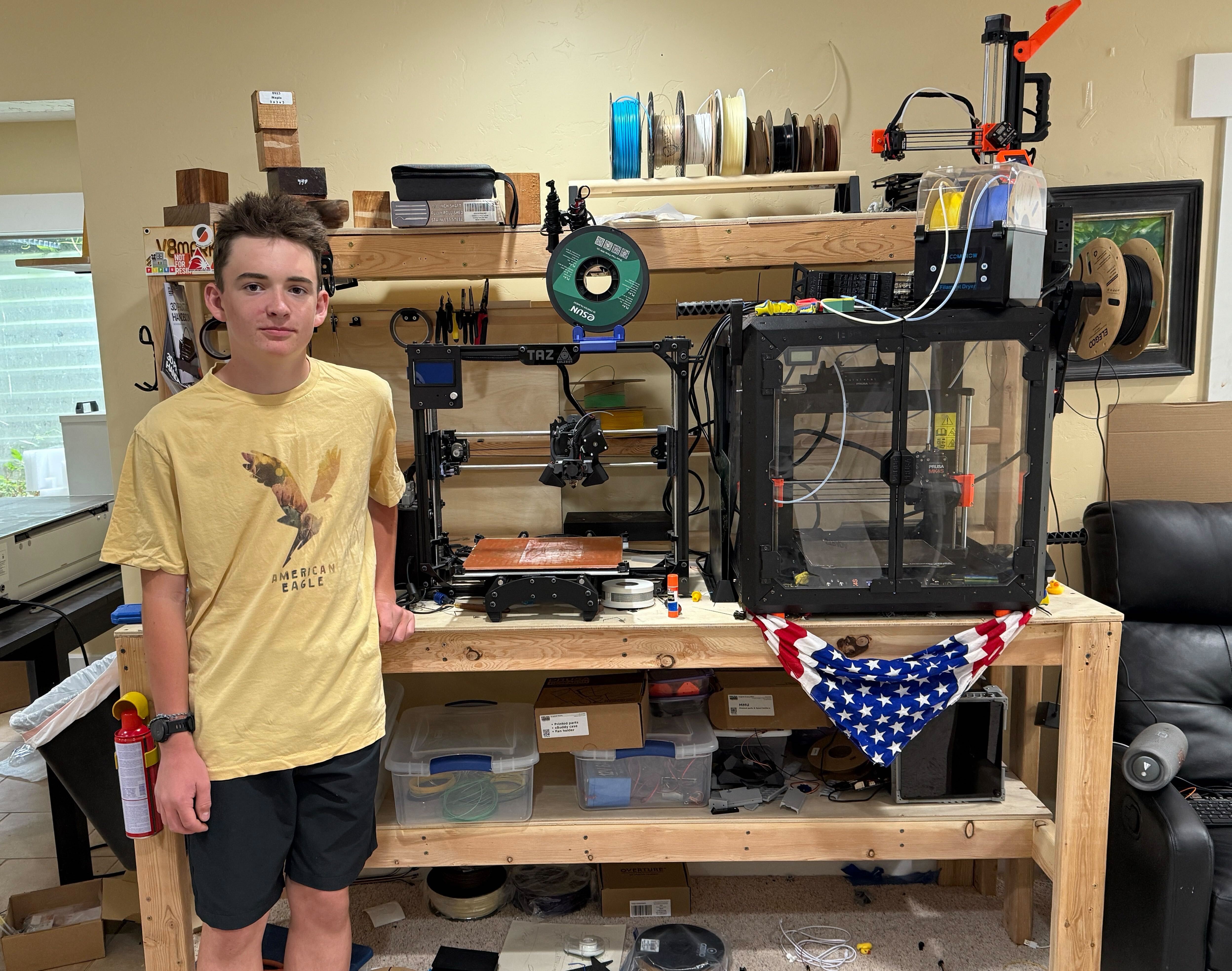teen boy stands with 3d printer