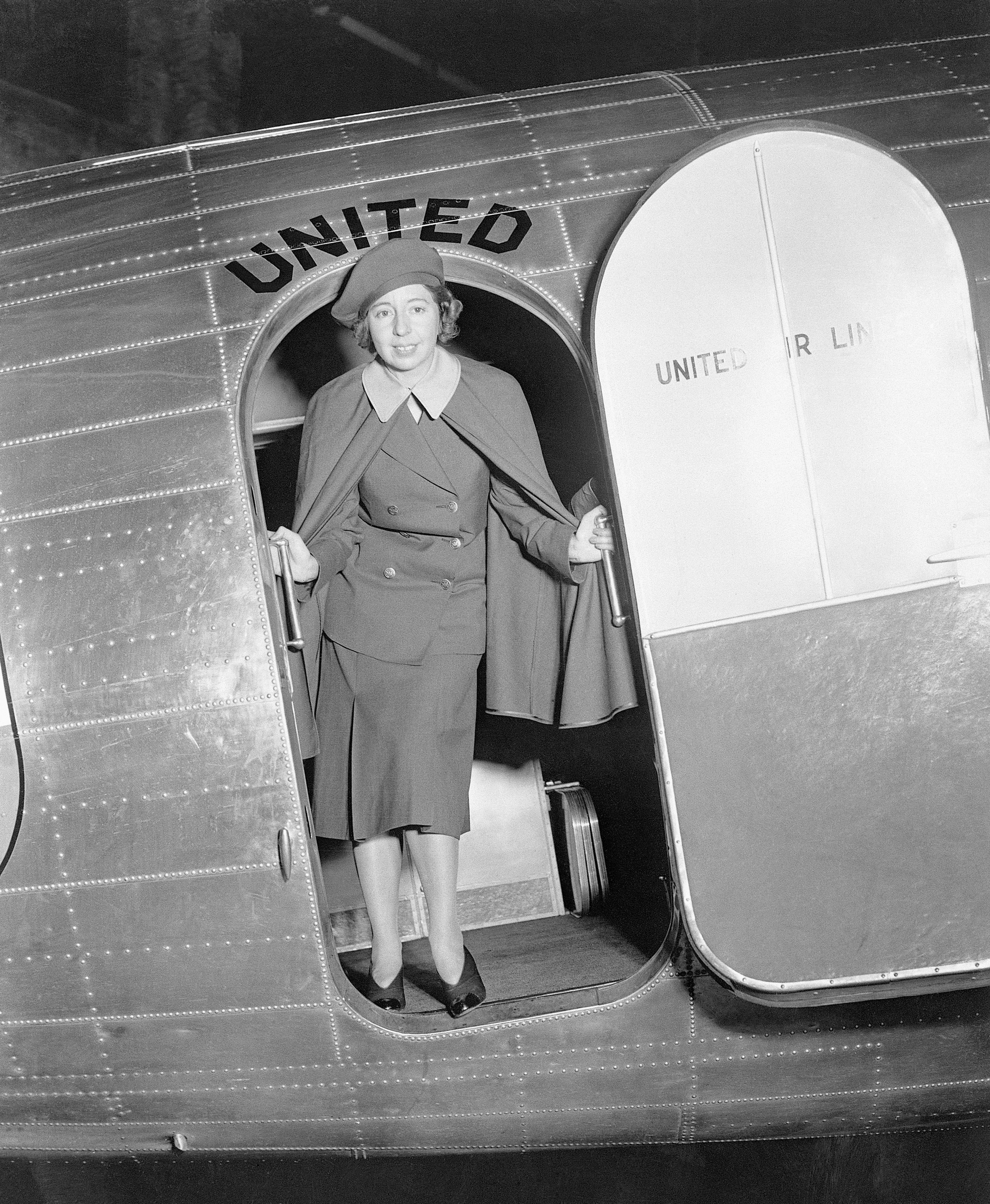 Black‑and‑white photograph of a middle-aged woman, Ellen E. Church, standing in the doorway of a United plane in her flight attendant uniform.