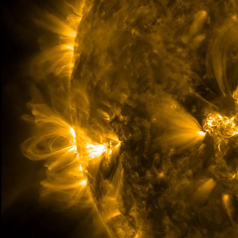 an active region of the sun. long wisps of energy are show in yellow and jetting out of the sun