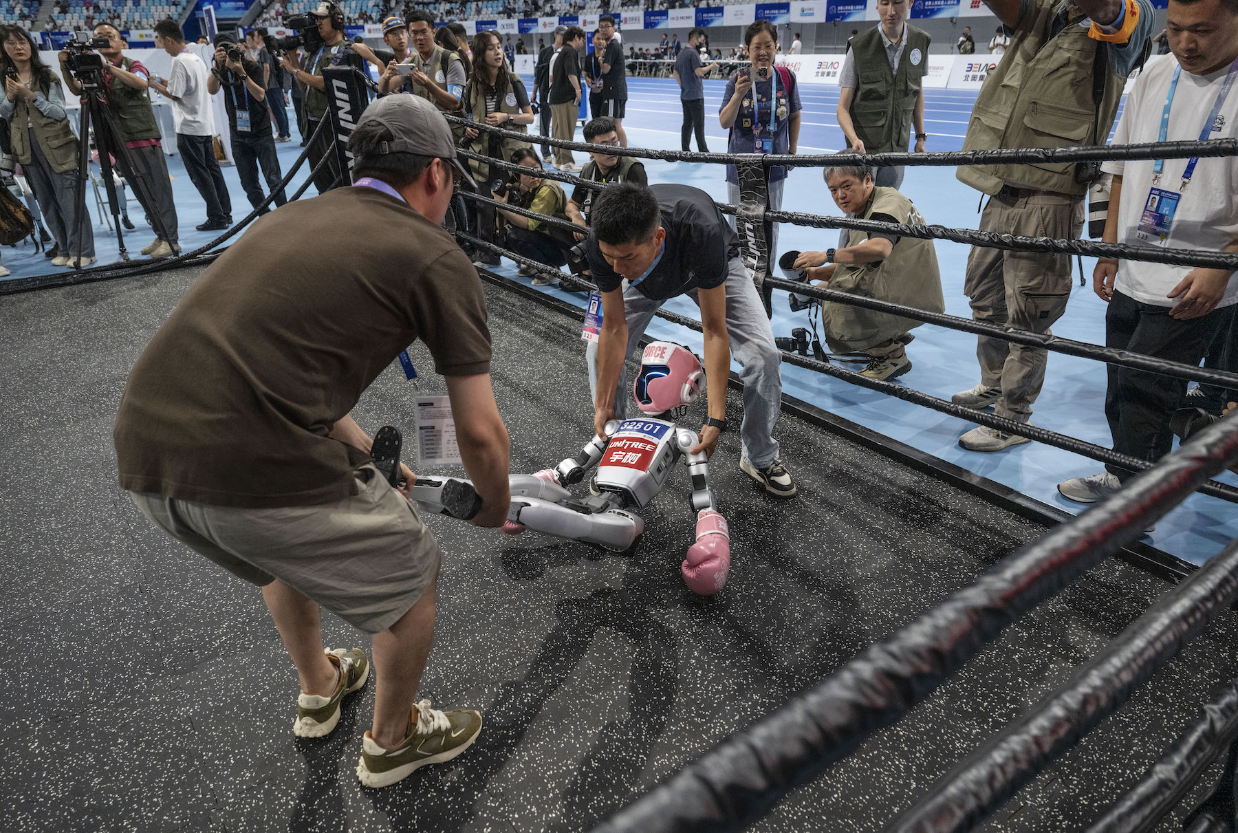 A humanoid robot is carried by technicians after being knocked out in a kickboxing match at the World Humanoid Robot Games