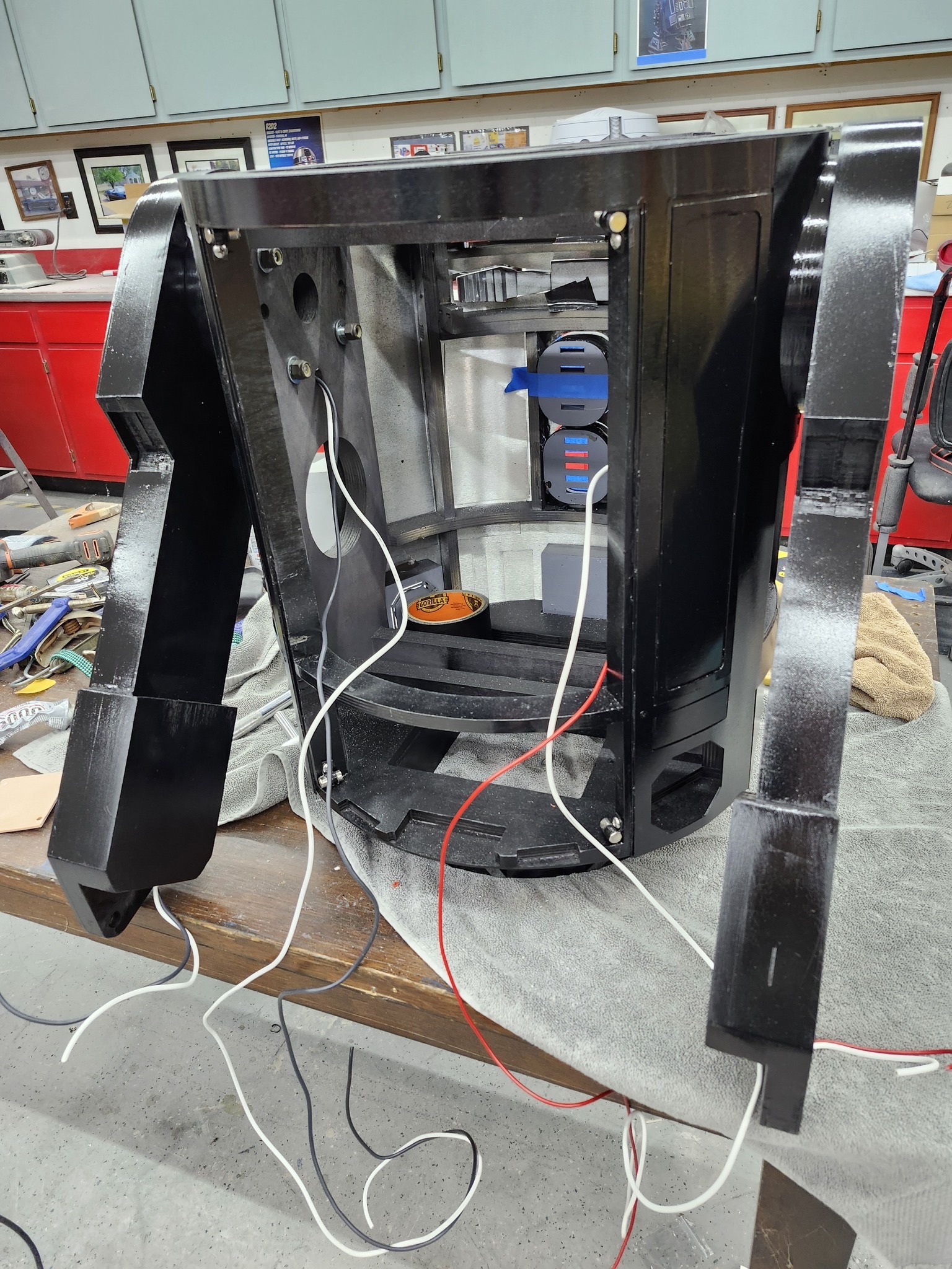 a droid in progress on a work bench. wires are hanging out