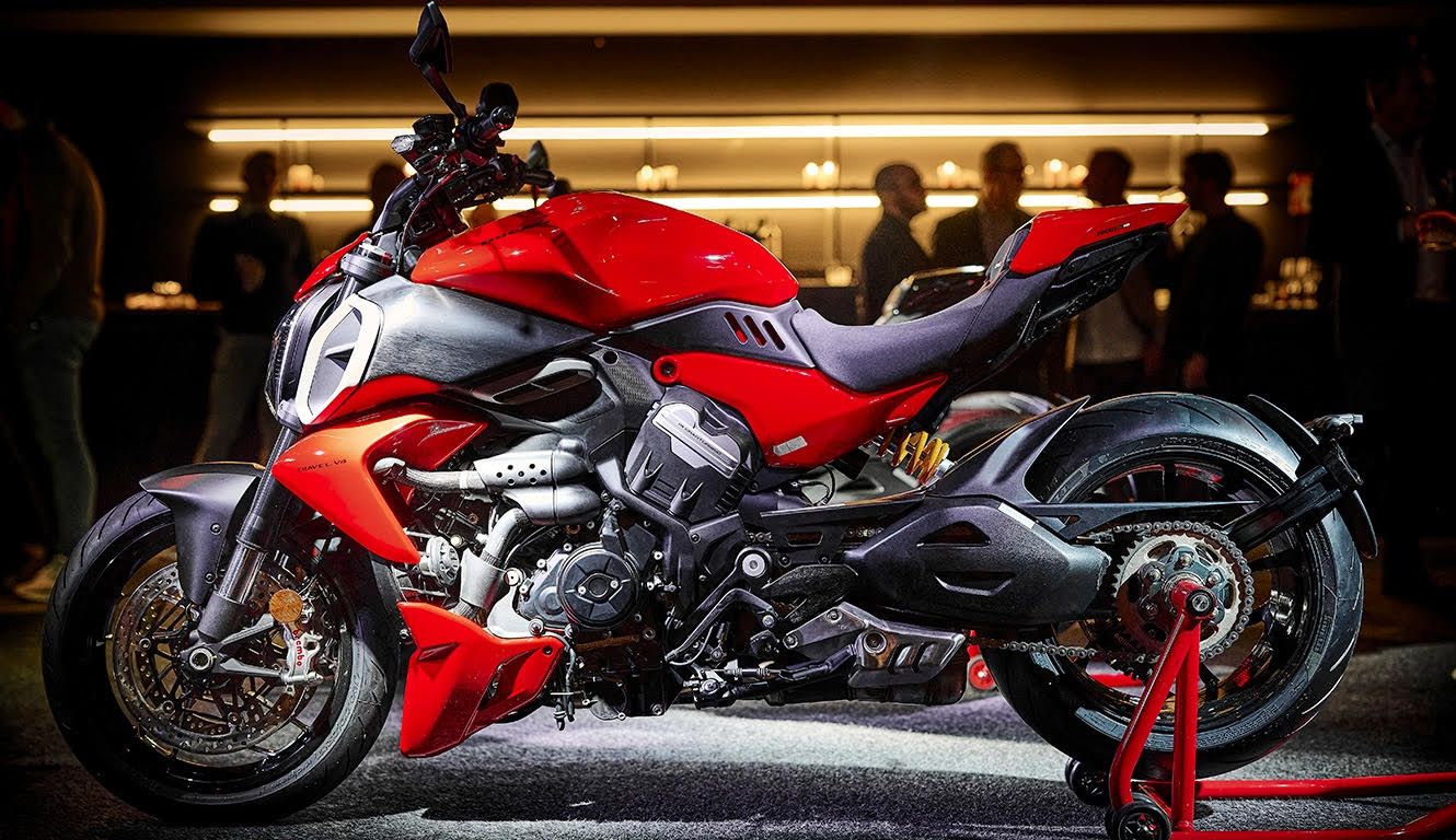 a red motorcycle inside a room while people mingle in the background