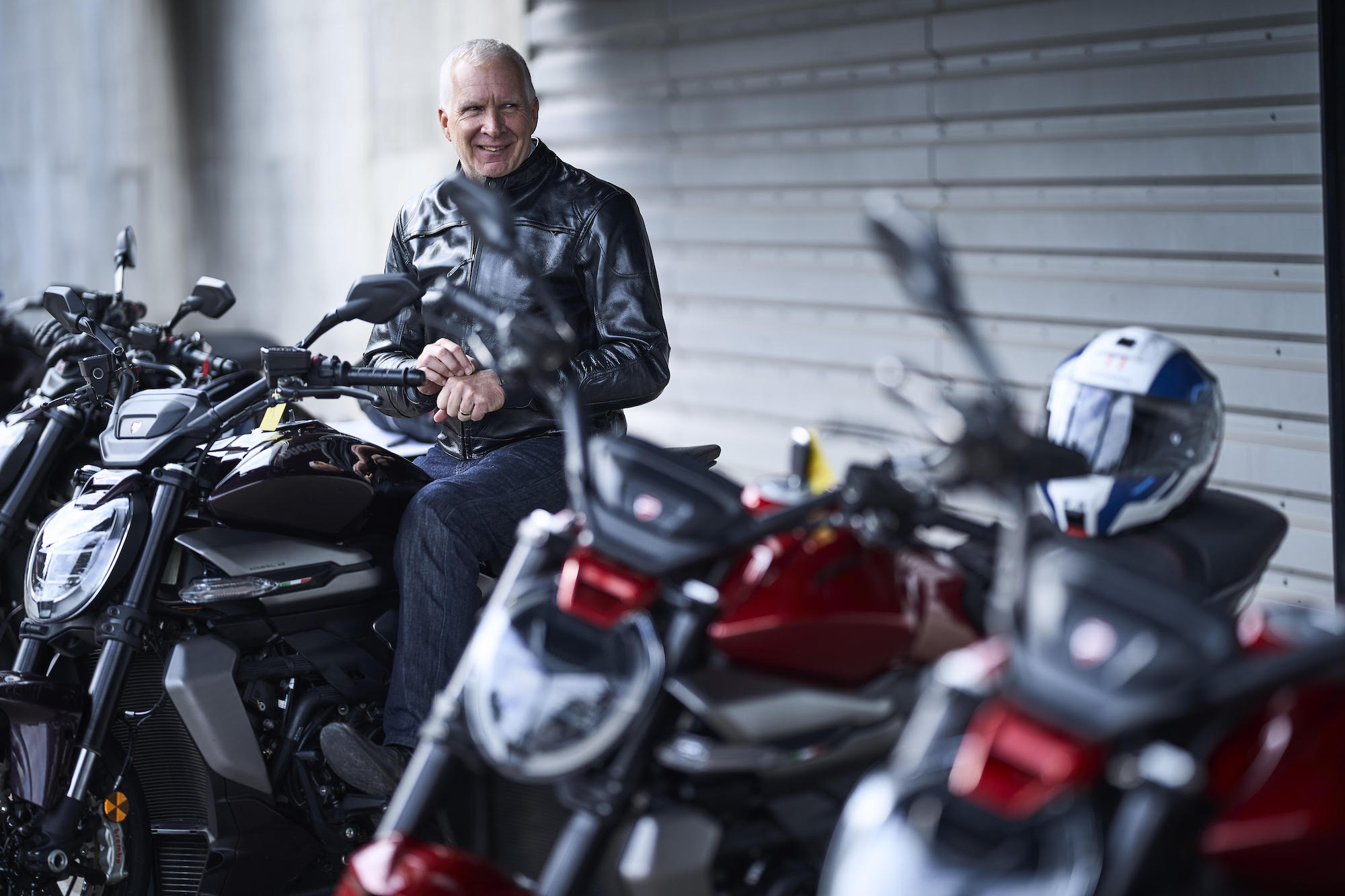 man with grey hair sits on row of motorcyles