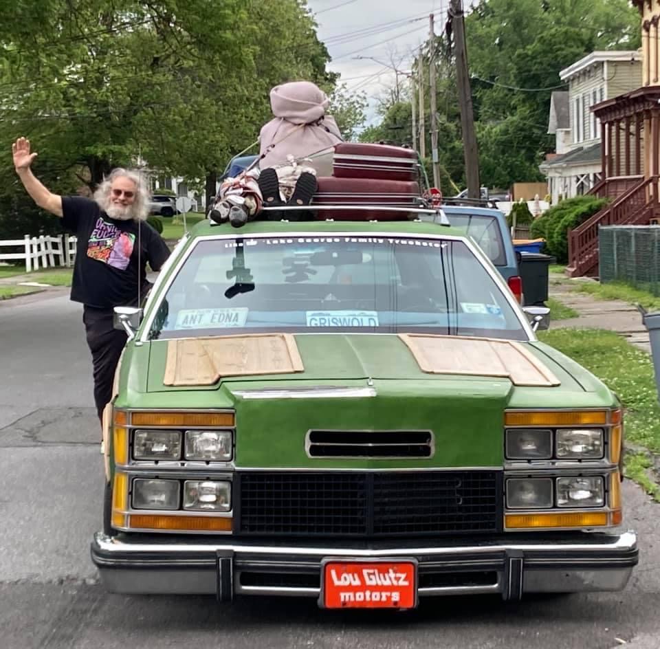 a man with beard poses with a station wagon