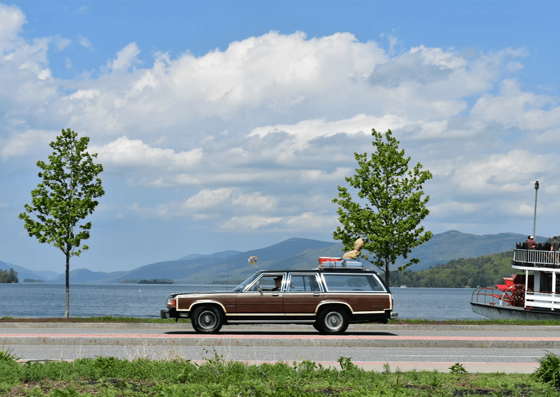 a station wagon driving by a lake