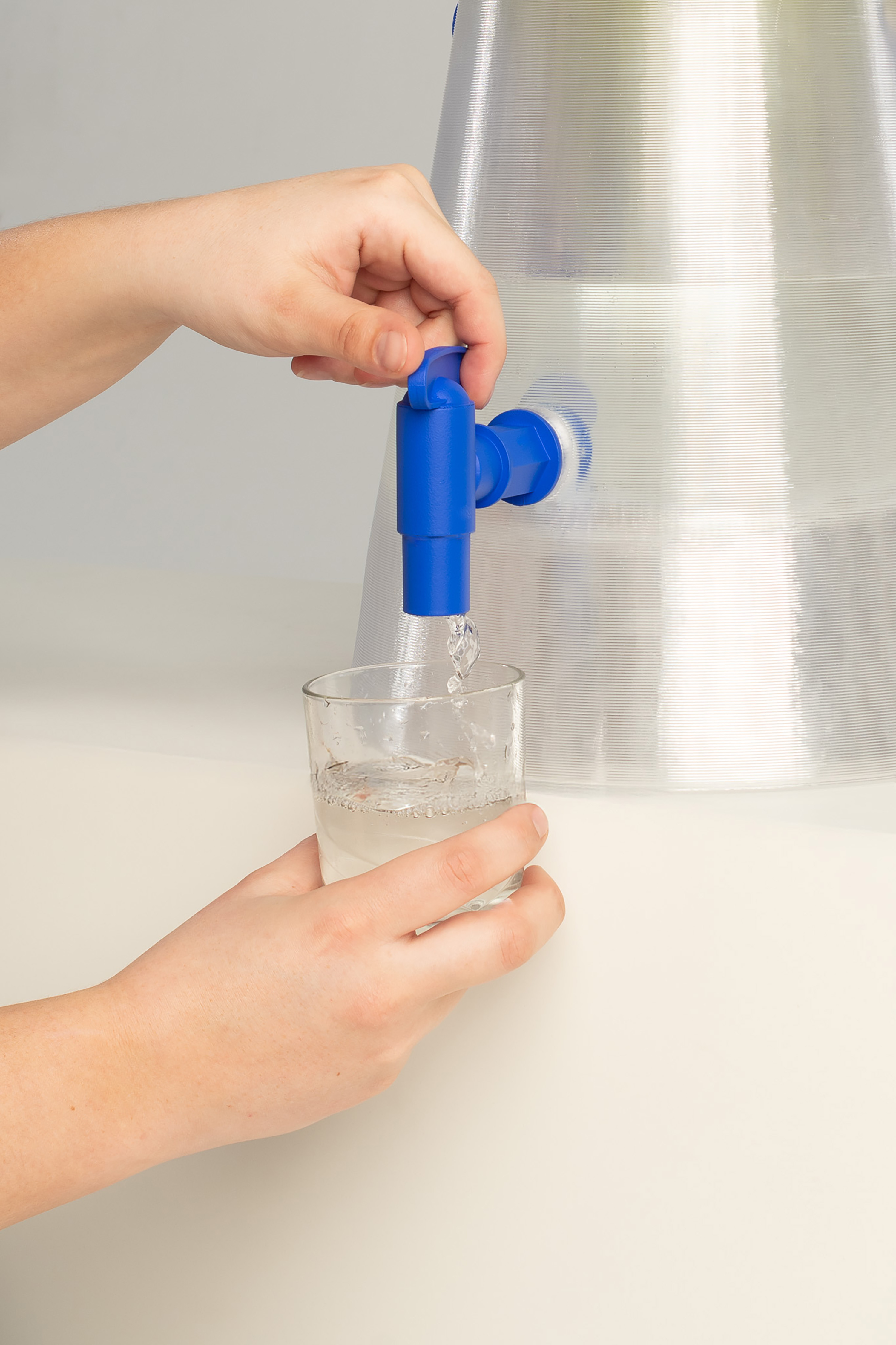 a person pours a glass of water from jug