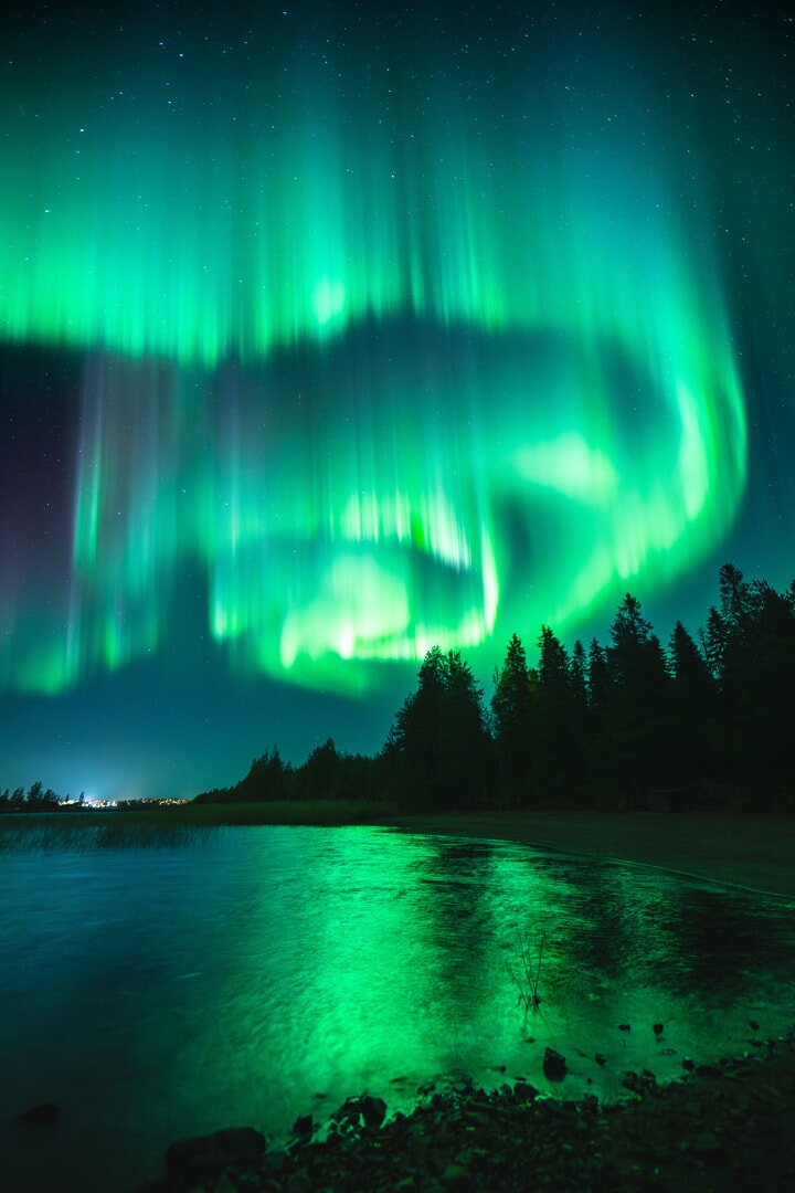 a green aurora circling around trees
