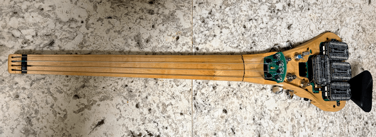 A four stringed wooden instrument with mini computer boards on the main body