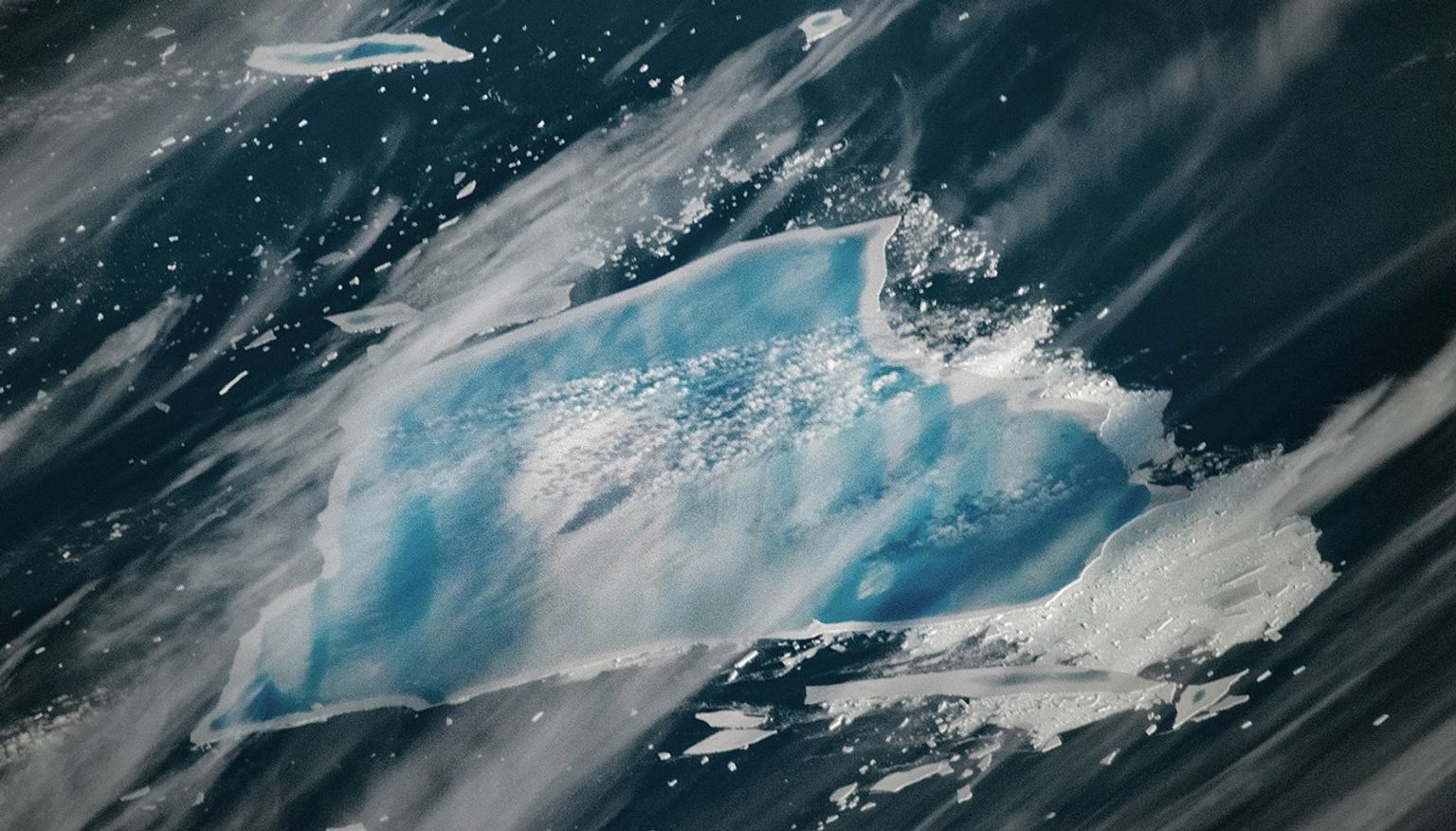 A satellite image of an iceberg taken showing blue pools of water