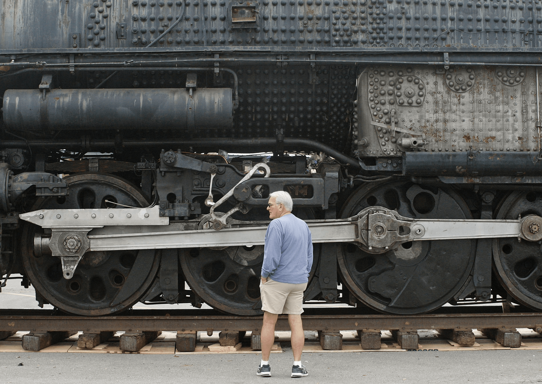 a man stands next to a large steam locomotive. he is much smaller by comparison